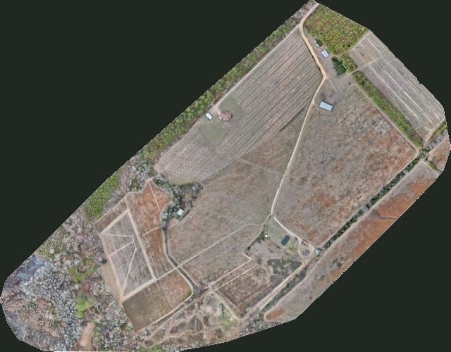 Stitched aerial drone map of a rural property showing fields, tree lines, roads, and buildings